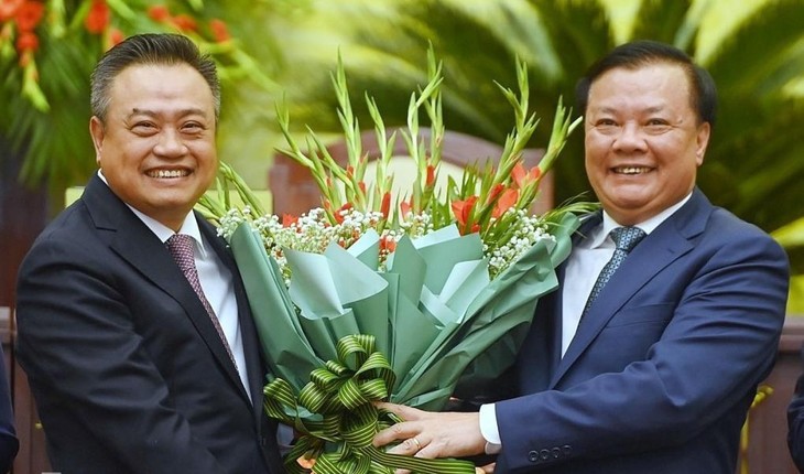 Tân Chủ tịch UBND TP. Hà Nội Trần Sỹ Thanh (trái) nhận hoa chúc mừng từ Bí thư Thành ủy Hà Nội Đinh Tiến Dũng. Ảnh: Giang Huy