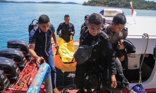 Cảnh sát Indonesia mang túi đựng xác và mảnh vụn máy bay lên bờ. Ảnh:AFP