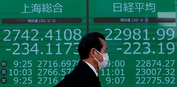 Người đàn ông đi qua bảng điện tử một công ty môi giới ở Tokyo (Nhật Bản). Ảnh:Reuters